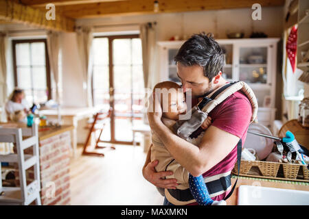 Père avec un bébé fille dans un transporteur à la maison. Banque D'Images