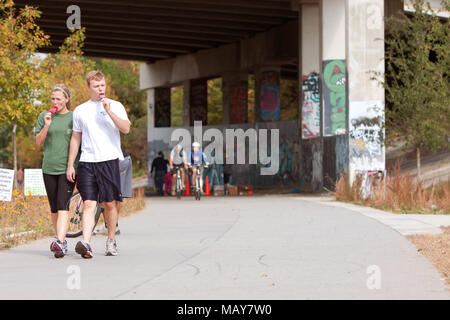 Un jeune couple marche et mange des sucettes glacées le long d'un chemin couvert de graffitis qui fait partie de la 22-mile de la ceinture d'Atlanta le 2 novembre 2013 à Atlanta, GA. Banque D'Images