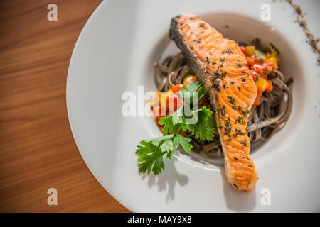 Plat de spaghetti sautées avec du saumon grillé sur le dessus de table en bois Banque D'Images