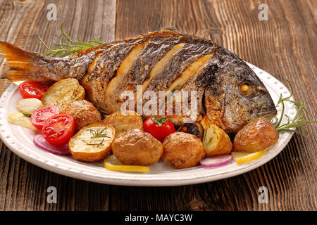 Poisson avec légumes rôtis dorada sur fond de bois Banque D'Images