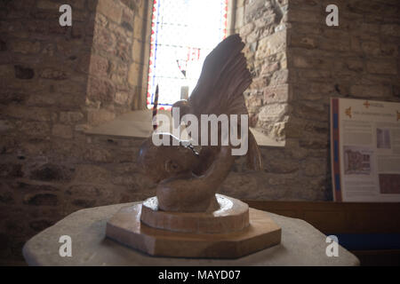 Sculpture de couverture de police à l'intérieur d'une église sur l'île Sainte (Lindisfarne), représentant un enfant soulevant une colombe, éclairé par la lumière de vitraux Banque D'Images