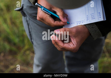 Homme tenant un bug et en prenant des notes statistiques Banque D'Images