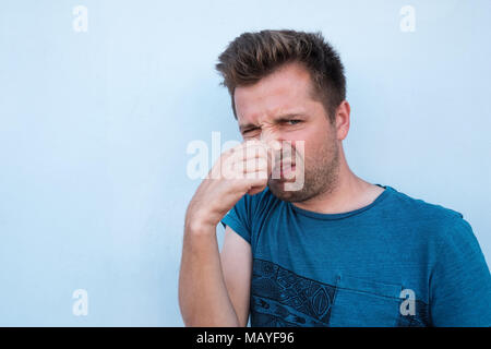Man in blue shirt fermer son nez à cause de mauvaise odeur. Banque D'Images