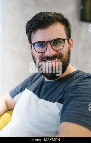 Close up d'un homme barbu portant des lunettes et souriant à l'appareil photo Banque D'Images