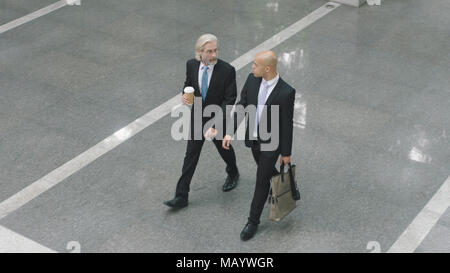 Portrait de deux dirigeants d'parler tout en marchant sur hall d'immeuble de bureaux modernes. Banque D'Images