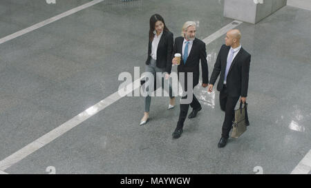 Portrait de trois dirigeants d'parler tout en marchant sur hall d'immeuble de bureaux modernes. Banque D'Images