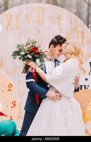 Happy wedding couple hugs doucement au grand vintage horloges en forêt d'automne. Décorations créatives Banque D'Images