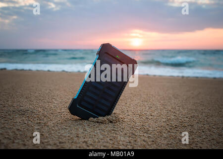 Petit panneau solaire portable près de l'océan Atlantique. Powerbank pour charger les téléphones portables et autres périphériques via USB. Batterie solaire au soleil sur la Banque D'Images