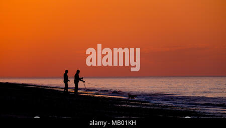 Trois amis sur la plage au coucher du soleil. Banque D'Images