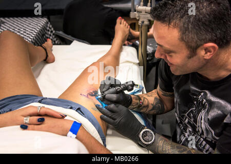 Conception d'un tatouage Race marque sur la cuisse d'une femme à la Convention de Tatouage de Cornwall. Banque D'Images