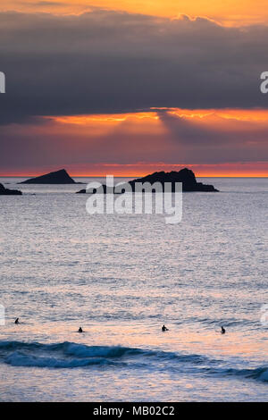 La Poule et le poussin de petites îles au large de pointe sont seeen Pentire en silhouette alors que le soleil se couche sur Cornwall dans Fistral. Banque D'Images