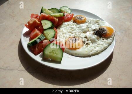 Oeufs au plat avec des tranches de concombre et de tomate sur le côté Banque D'Images