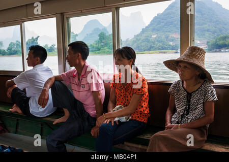 Yangshuo, Chine - le 2 août 2012 : Les personnes voyageant dans un bateau dans le fleuve Li, près de la ville de Yangshuo, en Chine. Banque D'Images