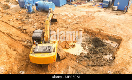 Vue aérienne de l'excavateur à chenilles commence à creuser sol préparation à la création de copropriété. voie hoe de travailler. La préparation du terrain avant la construction d'habitation en copropriété Banque D'Images