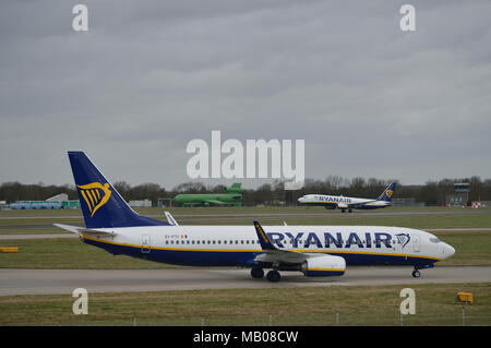 Le roulage des avions de Ryanair à l'aéroport de Londres Stansted Ryanair comme un autre avion décolle dans l'arrière-plan Banque D'Images