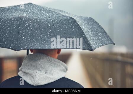 Homme avec parapluie dans la pluie. En ville météo sombres. Selective focus sur la goutte. Banque D'Images