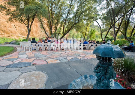 Un mariage en plein air à l'ombre des chênes en face d'une rivière à un lieu de la Californie, avec une statue de brun à l'avant-plan Banque D'Images