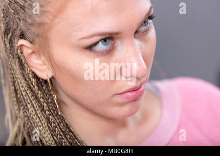 Jolie femme blonde avec des yeux bleus à l'âme jusqu'à une grave expression pensive dans un close up portrait high angle portrait Banque D'Images