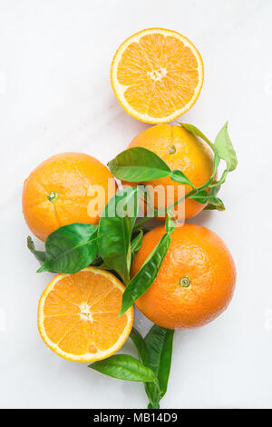 Bouquet de mûres entières et des moitiés juteux Orange avec des feuilles vertes sur table de marbre de pierre blanche. Vitamines Régime Sain Detox Fruits tropicaux d'été végétalien Co Banque D'Images