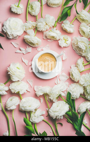 Matin de printemps concept. Télévision à jeter de tasse de café entouré de lumière blanche ranunculus fleurs sur fond rose, vue du dessus Banque D'Images