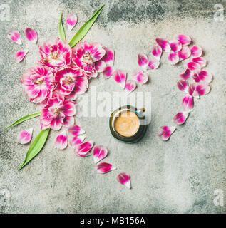 Matin de printemps concept. Télévision à jeter de tasse de café entouré de fleurs tulipe rose et les pétales en forme de coeur sur fond de marbre gris, top vie Banque D'Images