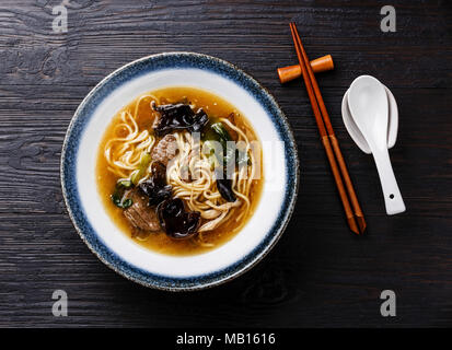 Blé d'Asie avec nouilles Ramen boeuf, champignons du bois et le chou pak-choï dans un bol sur fond de bois foncé Banque D'Images