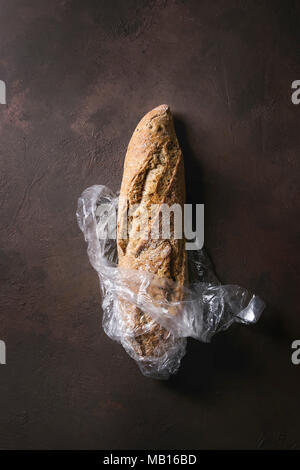 Du pain artisanal frais cuit le pain de grains entiers dans le sac en plastique brun foncé sur fond de texture. Vue de dessus, copiez l'espace. Banque D'Images