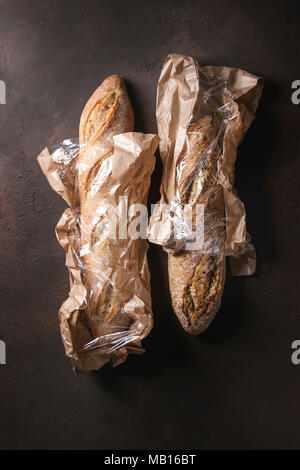 Deux loafs de seigle et artisan frais cuit le pain blanc en sac de papier du marché brun foncé sur fond de texture. Vue de dessus, copiez l'espace. Banque D'Images