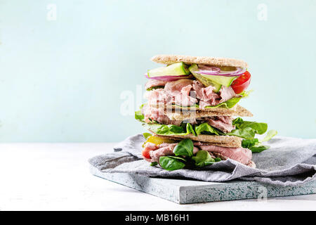 Boeuf et légumes sandwiches avec des tranches de viande, concombre, salade verte, le seigle le pain de grains entiers dans la pile sur plateau en bois avec textil plus serviette gre gris Banque D'Images