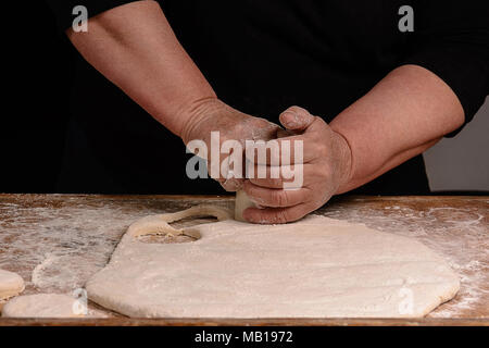 Granny serre un verre d'un cercle dans une pâte sur la table 2018 Banque D'Images