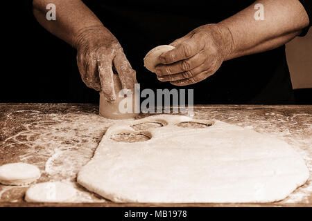 Granny serre un verre d'un cercle dans une pâte sur la table 2018 Banque D'Images