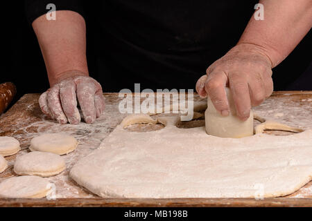 Granny serre un verre d'un cercle dans une pâte sur la table 2018 Banque D'Images