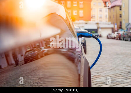 Close up du bloc d'alimentation branché sur une voiture électrique en cours de charge Banque D'Images