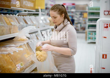 Belle jeune femme achète jetons sur poids dans les supermarchés Banque D'Images