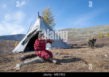 Garçon tsaatan, vêtu d'un traditionnel deel, avec arc et flèches dans une taïga du nord de la Mongolie Banque D'Images