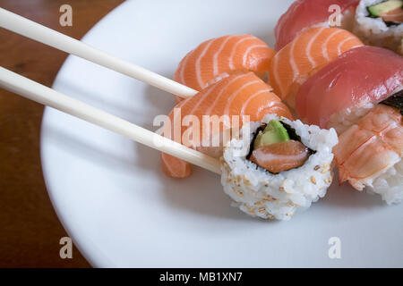 Sushis nigiri saumon frais entre les baguettes avec nigiri uramaki crevettes, et le thon nigiri Banque D'Images