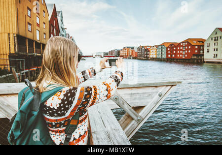 'Woman taking photo par visite en Norvège smartphone vacances style scandinave extérieur maisons colorées landmarks Trondheim city arch Banque D'Images