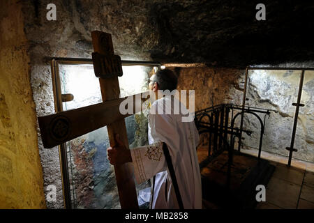 Jérusalem, Israël 6 Avril 2018 : Un pèlerin copte orthodoxe avec une croix en bois kissing fresque ancienne décorant les murs de la chapelle de l'invention de la Sainte Croix à l'intérieur de l'église du Saint Sépulcre pendant le vendredi saint orthodoxe de la semaine sainte dans la vieille ville de Jérusalem de l'est Israël. Les chrétiens orthodoxes du monde entier commémorer des événements autour de la crucifixion de Jésus Christ, jusqu'à sa résurrection le jour de Pâques. Credit : Eddie Gerald/Alamy Live News Banque D'Images