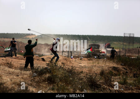 (180406) -- GAZA, 6 avril 2018 (Xinhua) -- un manifestant palestinien utilise une fronde pour lancer des pierres sur des soldats israéliens lors d'affrontements sur la frontière Gaza-Israel, est de la ville de Gaza, le 6 avril 2018. Des centaines de manifestants palestiniens ont commencé vendredi pour mettre le feu à des dizaines de pneus de voiture près de la frontière entre l'est de Gaza et Israël dans une tentative de rendre un bouclier de fumée noire pour se protéger des tirs des soldats israéliens. (Xinhua/Stringer) (ZF) Banque D'Images