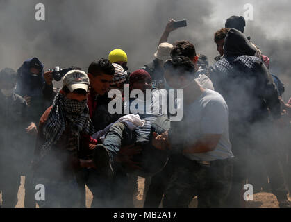 (180406) -- GAZA, 6 avril 2018 (Xinhua) -- des manifestants palestiniens transportent un homme blessé lors d'affrontements sur la frontière Gaza-Israel, est de la ville de Gaza, le 6 avril 2018. Des centaines de manifestants palestiniens ont commencé vendredi pour mettre le feu à des dizaines de pneus de voiture près de la frontière entre l'est de Gaza et Israël dans une tentative de rendre un bouclier de fumée noire pour se protéger des tirs des soldats israéliens. (Xinhua/Stringer) (ZF) Banque D'Images