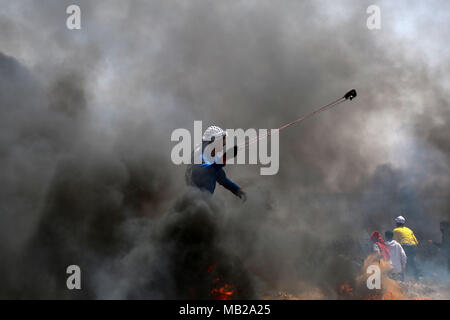 (180406) -- GAZA, 6 avril 2018 (Xinhua) -- un manifestant palestinien utilise une fronde pour lancer des pierres sur des soldats israéliens lors d'affrontements sur la frontière Gaza-Israel, est de la ville de Gaza, le 6 avril 2018. Des centaines de manifestants palestiniens ont commencé vendredi pour mettre le feu à des dizaines de pneus de voiture près de la frontière entre l'est de Gaza et Israël dans une tentative de rendre un bouclier de fumée noire pour se protéger des tirs des soldats israéliens. (Xinhua/Stringer) (ZF) Banque D'Images