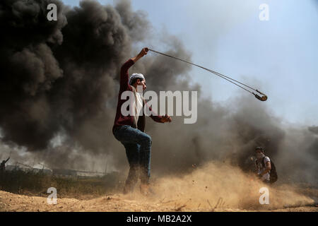 (180406) -- GAZA, 6 avril 2018 (Xinhua) -- un manifestant palestinien utilise une fronde pour lancer des pierres sur des soldats israéliens lors d'affrontements sur la frontière Gaza-Israel, est de la ville de Gaza, le 6 avril 2018. Des centaines de manifestants palestiniens ont commencé vendredi pour mettre le feu à des dizaines de pneus de voiture près de la frontière entre l'est de Gaza et Israël dans une tentative de rendre un bouclier de fumée noire pour se protéger des tirs des soldats israéliens. (Xinhua/Stringer) (ZF) Banque D'Images