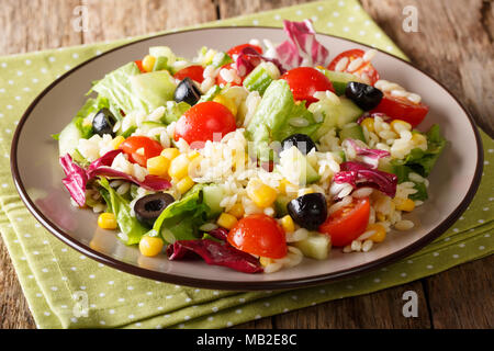 Savoureuse salade composée de légumes, de riz et de laitue sur une assiette sur une table horizontale. Banque D'Images
