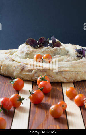 Tarte filo spirale burek avec tomates cerise sur table en bois Banque D'Images