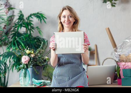 Photo de femme fleuriste avec une feuille blanche de l'ordinateur portable sur fond de plantes d'intérieur Banque D'Images