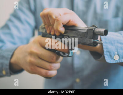 Les mains d'hommes d'armes à feu de rechargement. Vue rapprochée. Banque D'Images