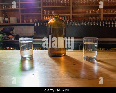 Cruche d'eau et tasses sur le dessus de bar brasserie le jour sombre Banque D'Images