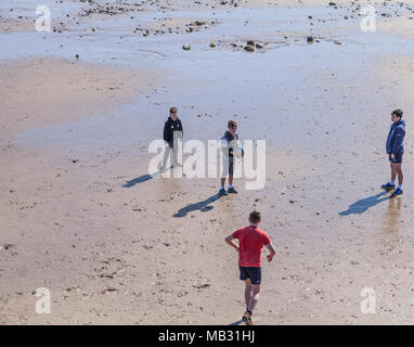 Un groupe de jeunes garçons à jouer au rugby sur la plage de Nice par la mer,Angleterre,UK Banque D'Images