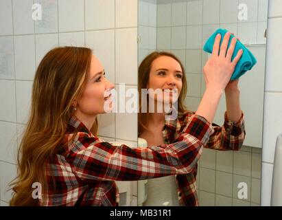 Travaux maison, young woman cleaning mirrir dans une salle de bains, Suède Banque D'Images