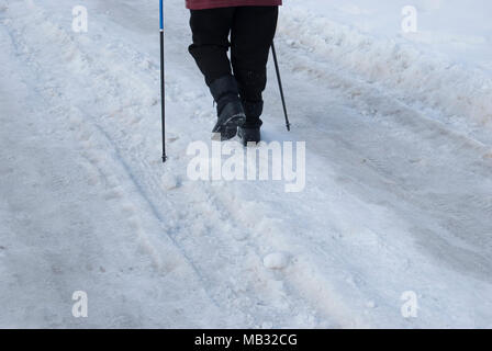 Les jambes d'une femme âgée engagés dans la marche nordique avec des bâtons. Vue arrière. Banque D'Images
